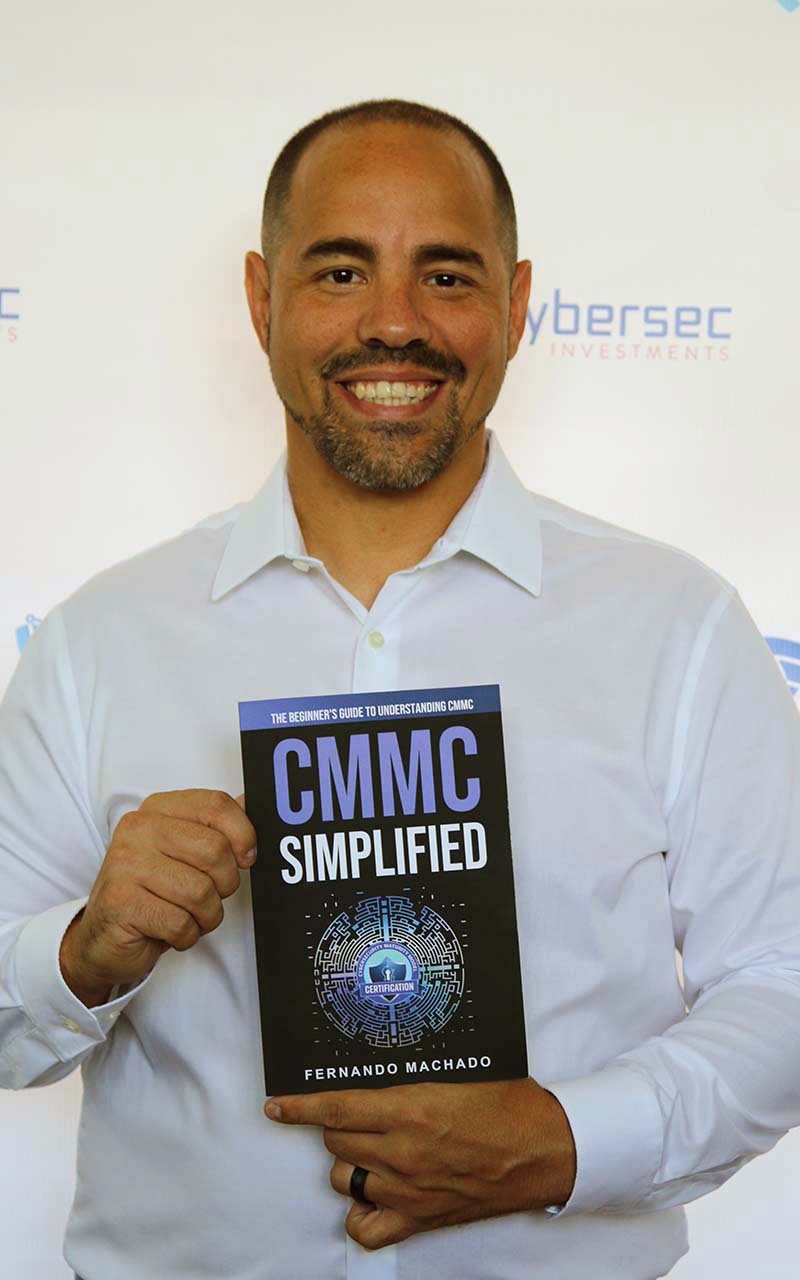 A man holding up a book with the words cmmc simplified on it.