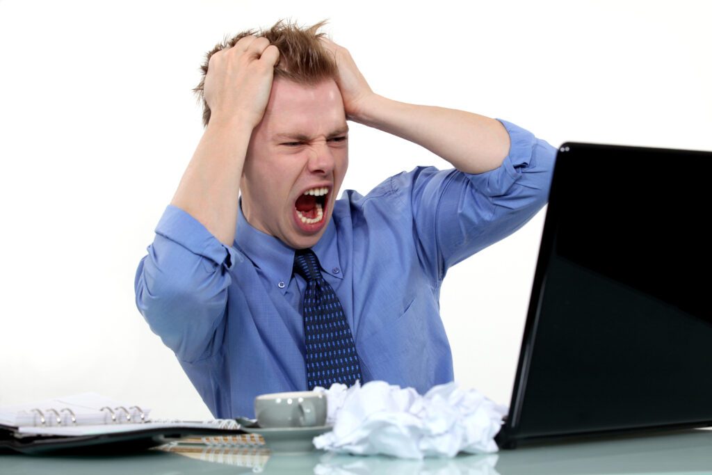 Frustrated businessman yelling at laptop.
