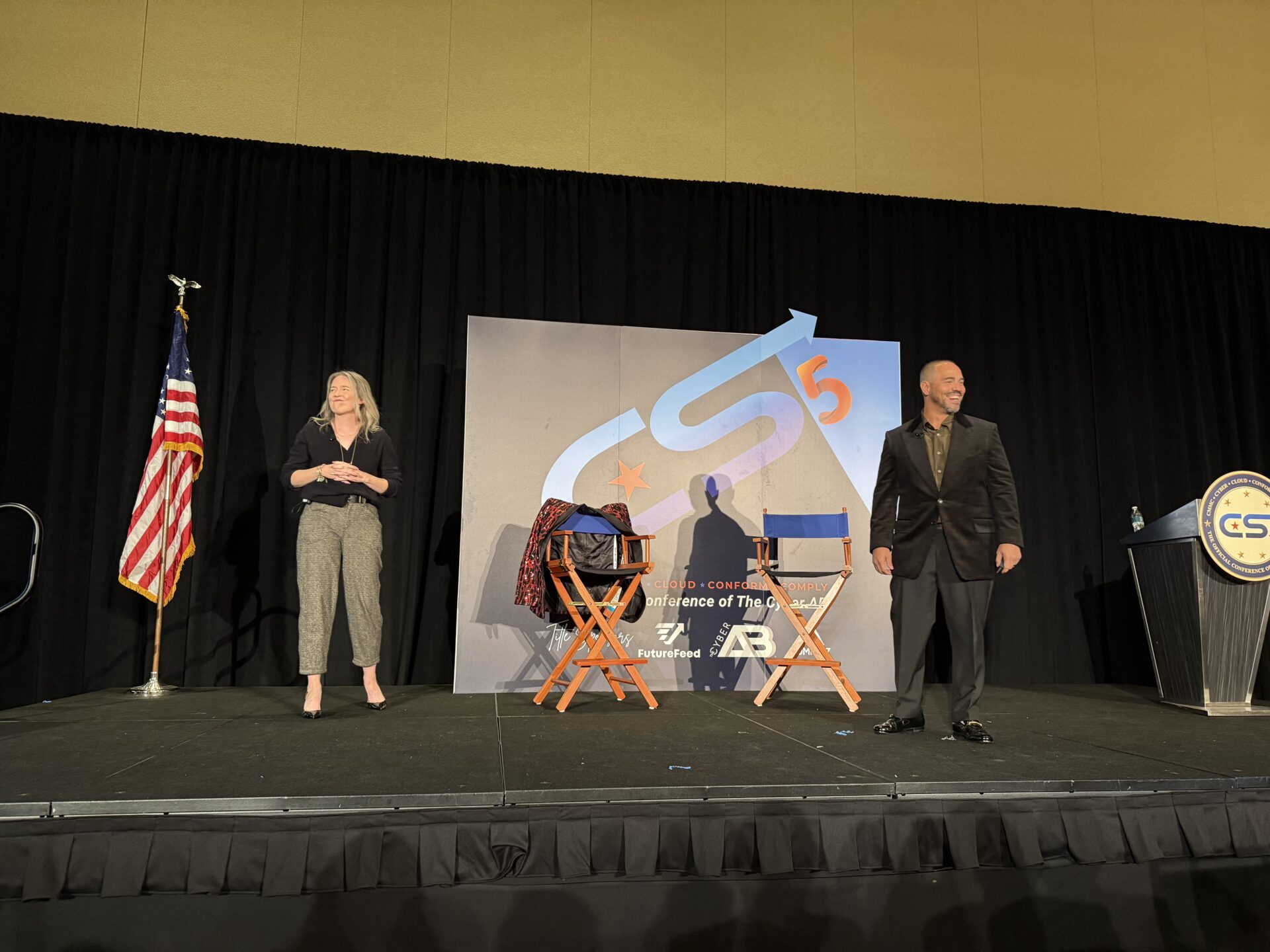 Two people on stage with chairs.