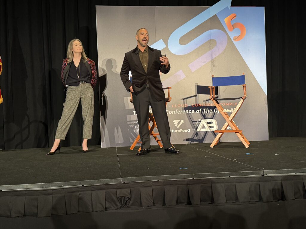 Two people speaking on a conference stage.
