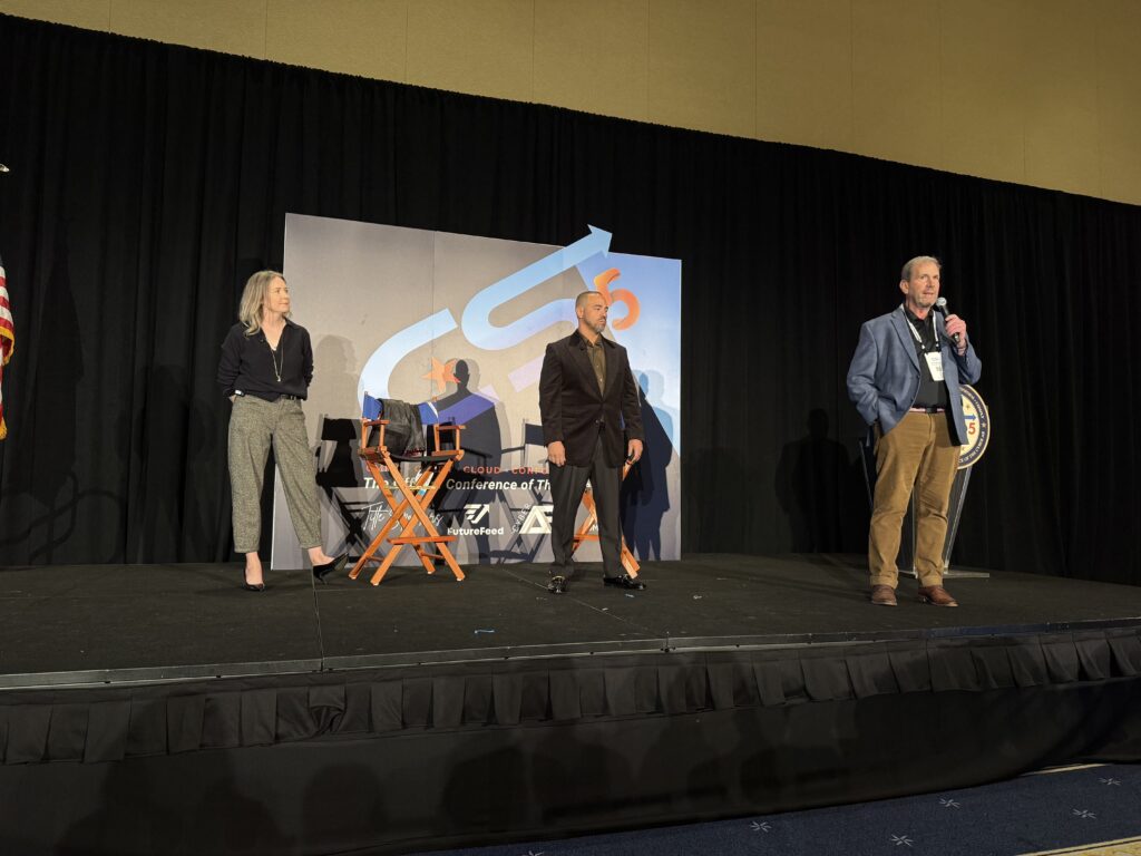 Three speakers on stage at a conference.